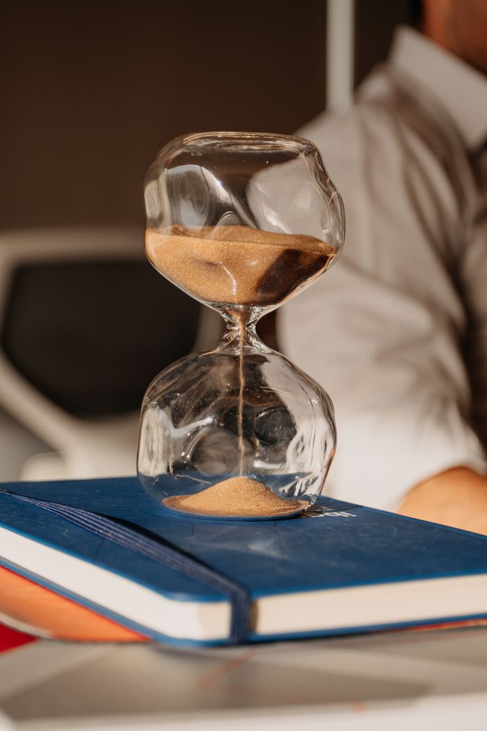 A glass hourglass with sand on books in a modern office environment.